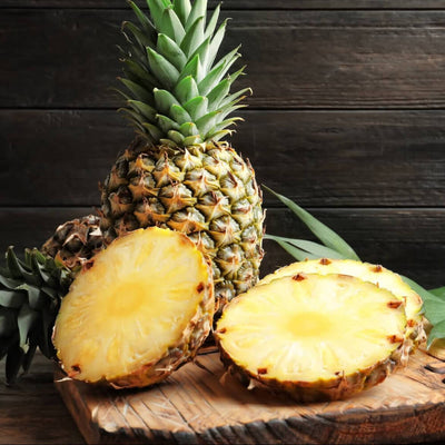 Ananas liegt ganz und geschnitten auf Holzbrett